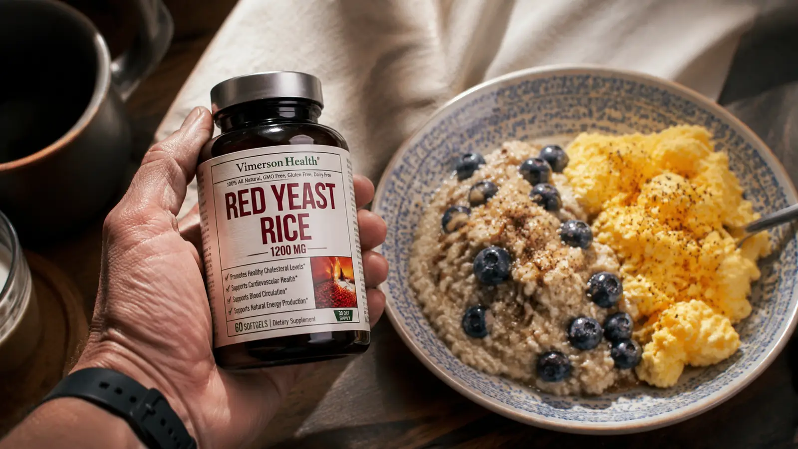 A hand in morning light holding out a softgel supplement bottle beside a plate of oats and eggs on a kitchen table
